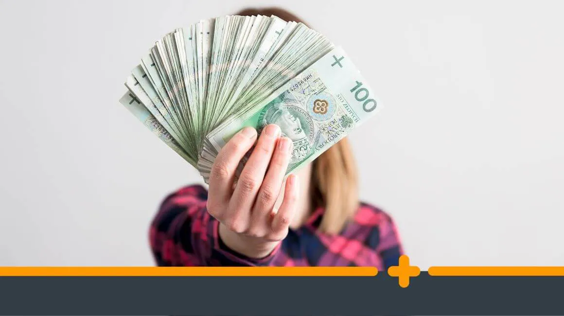 Kobieta trzymająca przed sobą wachlarz banknotów 100 złotych