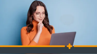 Młoda kobieta w okularach patrzy na laptop, zastanawiając się nad decyzją finansową